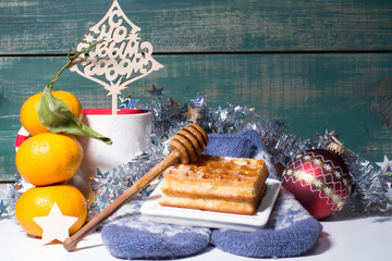 Christmas decoration. christmas red ball, waffles, mug, mandarin, tinsel, lights and mittens