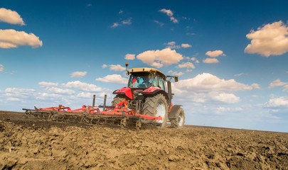 Fototapeta premium Farmer in tractor preparing land with seedbed cultivator