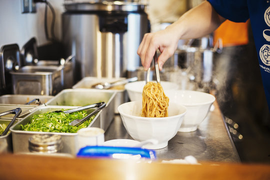 A Ramen Noodle Shop Kitchen. A Chef Preparing Bowls Of Ramen Noodles In Broth, A Speciality And Fast Food Dish. 