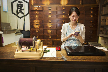 A traditional wagashi sweet shop. A woman working at a desk using a laptop and phone.  