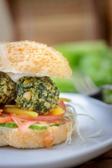 Shot of falafel burger whith the fresh vegetables and falafel balls inside it.