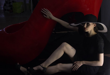 Красивая сексуальная девушка модель в сексуальном образе длинные эротичные ноги на фоне красной структуры и люминесцентной лампы