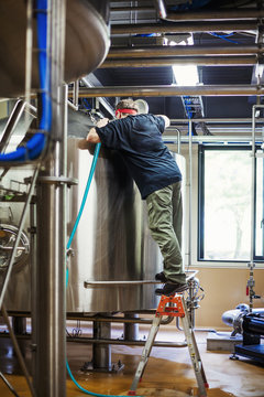 Man working in a brewery adjusting and checking the machinery which transfers the brewed beer around the processing plant. 