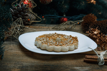 Beautiful concept. Close up Chocolate cookies on a white plate on a wooden background. Nearby stands a Christmas tree, toys, garlands and Christmas toys.