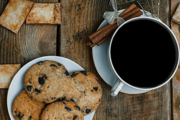 Beautiful concept. Chocolate cookies on a white plate on a wooden background and tea. Nearby stands a Christmas tree, toys, garlands and Christmas toys.