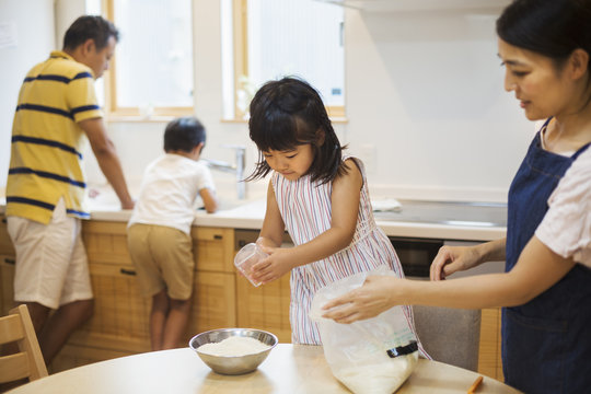 Family home. Two parents and two children preparing a meal. 