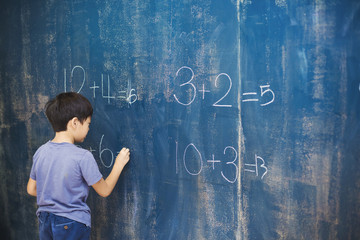 Boy writing in chalk on blackboard