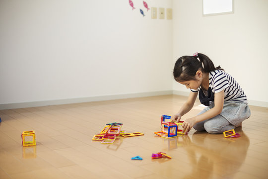 Girl sitting playing with coloured geometric shapes
