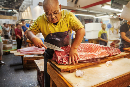 Fishmonger working filleting large fish on  slab
