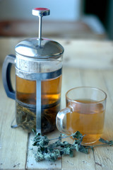 Green herbal tea in a teapot and cup on a wooden background.