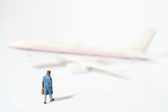 Toy businessman / View of miniature toy, businessman walking and airplane on white background.