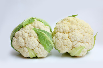 two cauliflowers with green leaf on white background