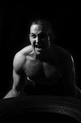 Male athlete raising tire in a gym.