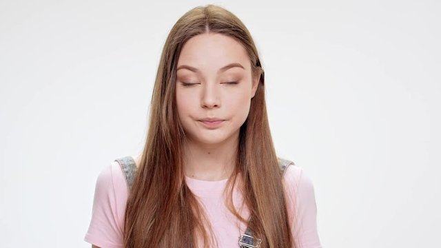 Sad young beautiful girl speaking over white background. Slow motion.
