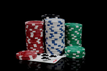 gambling poker chips and playing cards on black background