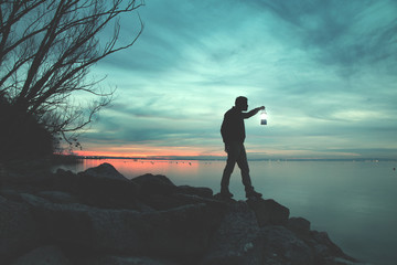Man with torch walking on rocks at lake in night