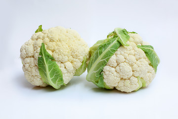 two cauliflowers with green leaf on white background