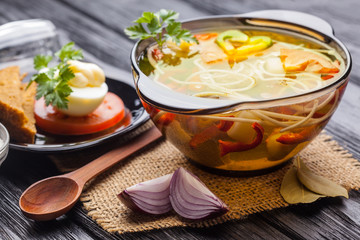 Fresh vegetable soup with noodles in a pot on black