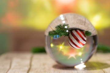 Eine Glaskugel mit einer Weihnachtskugel und Tannenzweigen im Inneren, auf dem Kopf stehend,
