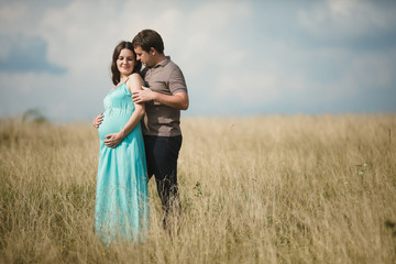 Beautiful pregnant woman with her husband posing outside