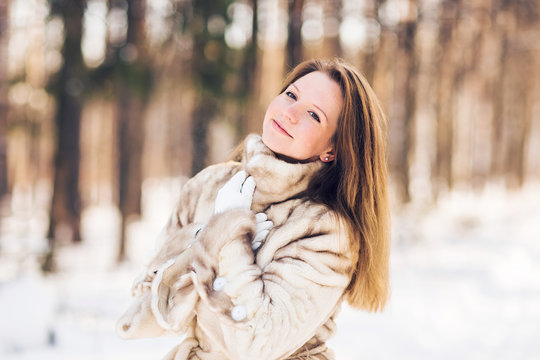 Winter portrait of young beautiful woman wearing fur coat. Snow winter beauty fashion concept.