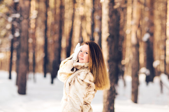 Winter portrait of young beautiful woman wearing fur coat. Snow winter beauty fashion concept.
