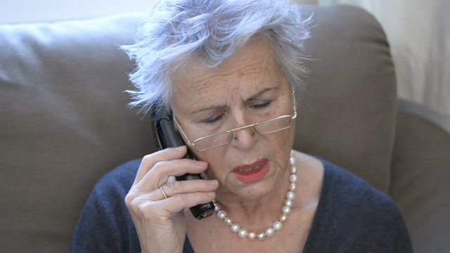 Attractive grey haired senior woman talking on the telefon about sad things