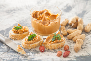 peanut butter in a bowl and sandwiches on a table, selective focus
