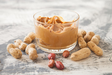 peanut butter in a bowl and sandwiches on a table, selective focus