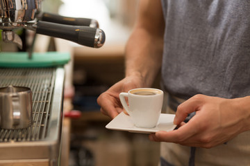 Barista serving a small cup of esspresso coffee