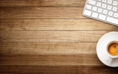 Keyboard and coffee cup on wooden background