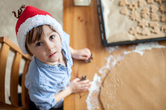 Adorable little boy, preparing cookies for christmas at home