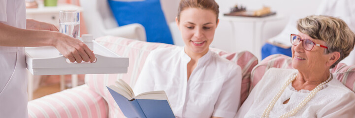 Senior woman and nurse holding tray with medicines