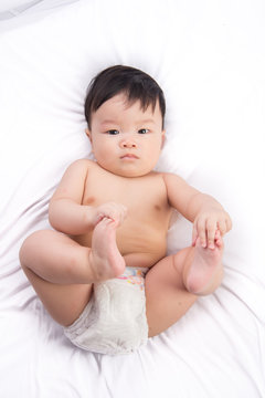 Portrait of cute Little asian boy 6 months old on the white bed