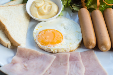 American breakfast with bread, fried eggs, sausage, bacon and salad
