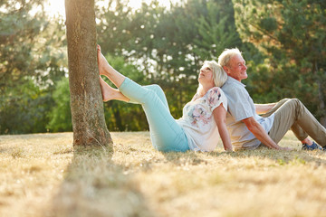 Senioren Paar sitzt Rücken an Rücken im Gras