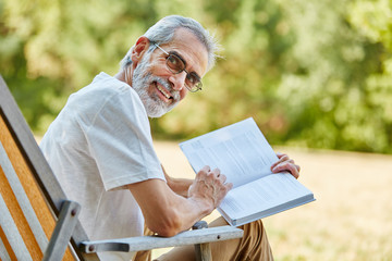 Rentner lächelt und hält ein Buch