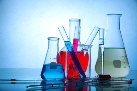 Different laboratory glassware with colored liquid with reflection