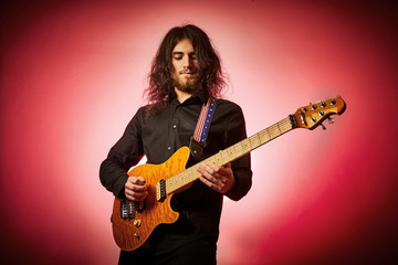 Obraz premium Ragazzo suona chitarra metal su fondo rosso