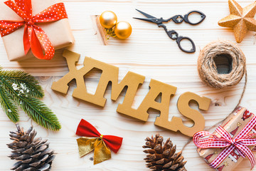 Christmas decoration with fir tree branch,word xmas,pine cones and gift on wooden background, top view, flat lay.