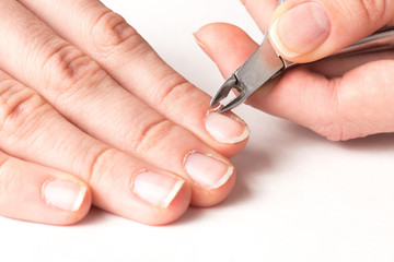 master of manicure cuts off the cuticle from the client fingers in nail salon
