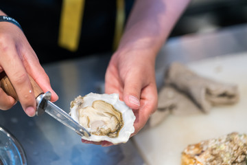 guy shucking an oyster with his bare hands
