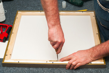 Craftsman working on frame in frame shop. Professional framer hand holding frame angle. Top view. Copy space