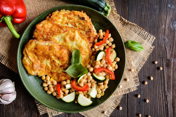 Roasted pork cutlets coated in cheese and breadcrumbs, served with chick peas and vegetable