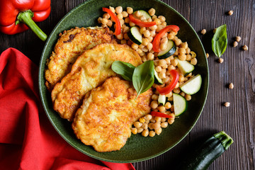 Roasted pork cutlets coated in cheese and breadcrumbs, served with chick peas and vegetable