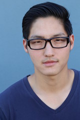 Fototapeta premium Asian man wearing glasses on a blue background - Stock image
