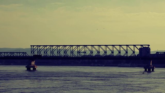 Cars, trucks and lorries crossing Danube river at bridge; 