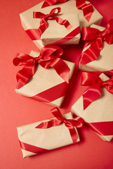 Christmas gifts wrapped in brown paper with silk bows on a bright red background