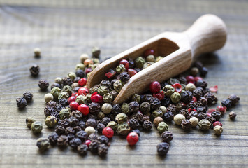 colour pepper with wooden scoop on wooden table