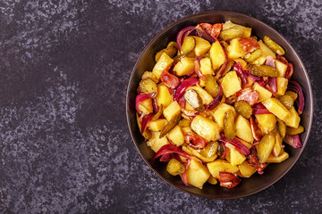 Homemade potato salad with bacon and pickles.